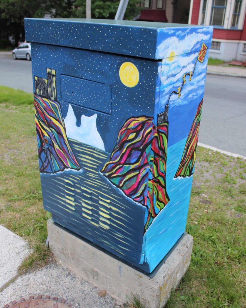 A utility box is decorated with a mural featuring an ocean landscape.