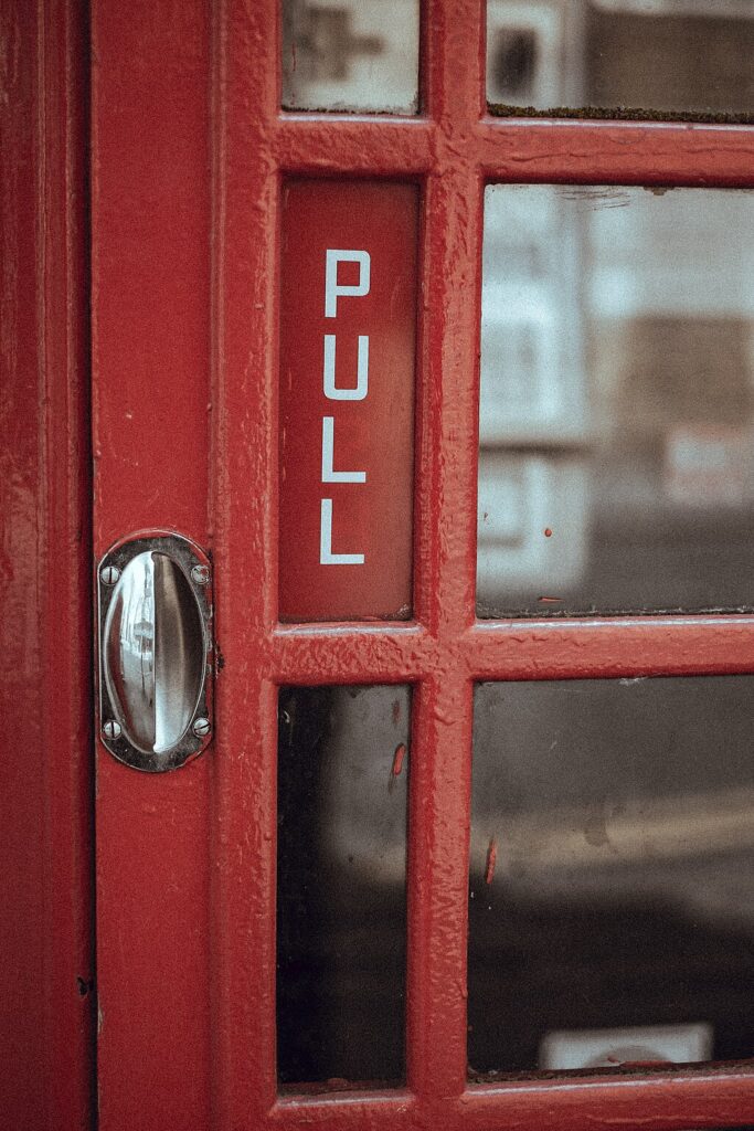 A sign on a red door reads "Pull". The door's handle gives no indications as to its function. 