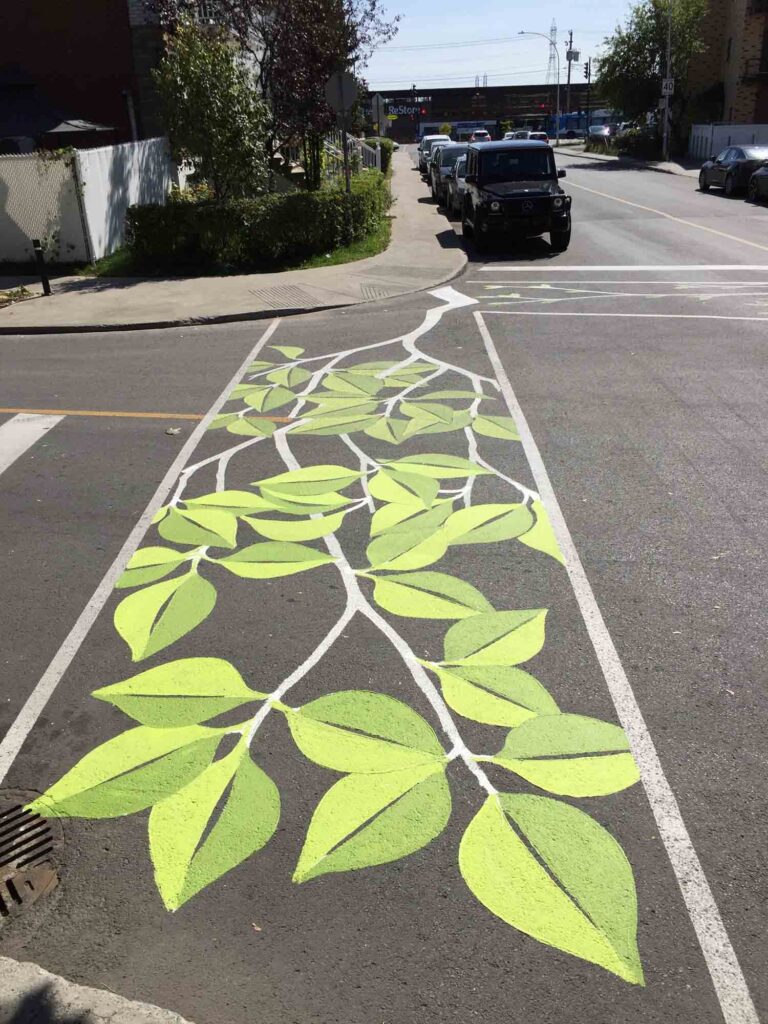 A crosswalk decorated with painting of spring leaves.