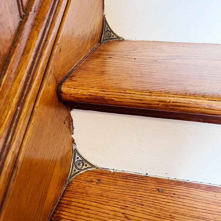 Small, triangular brass corners fit into the joint of stairs to prevent dust from collecting.