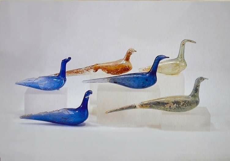 Six glass birds in blue, orange, and clear glass. The body of the bird is designed to hold perfume.