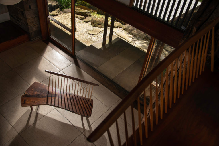 Taken from a above, a wooden bench sits in front of a large glass window.